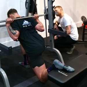 Justin Maker coaching a pt client on a smith machine